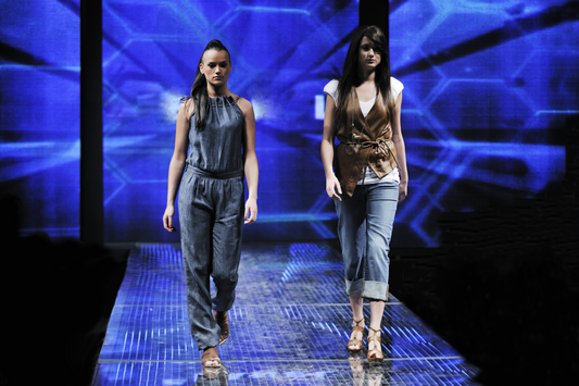 Two women wearing denim outfits walking a fashion runway.